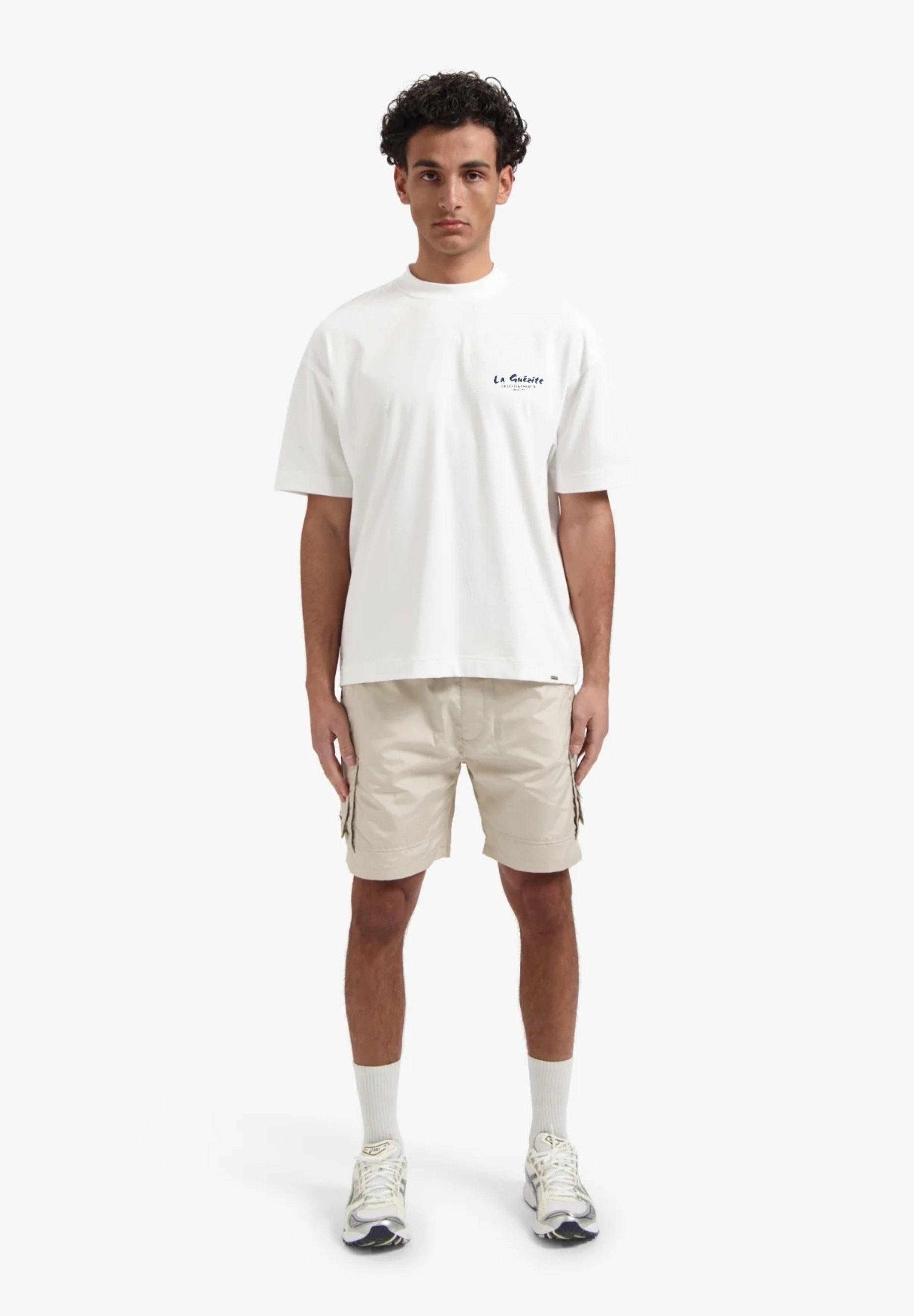 Person wearing a white t-shirt and beige shorts on a white background