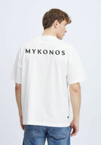 Person wearing a white t-shirt with 'MYKONOS' printed on the back against a light gray background