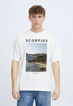 Person wearing a white t-shirt with 'Ibiza' on the back, standing by a pool with mountains in the background.